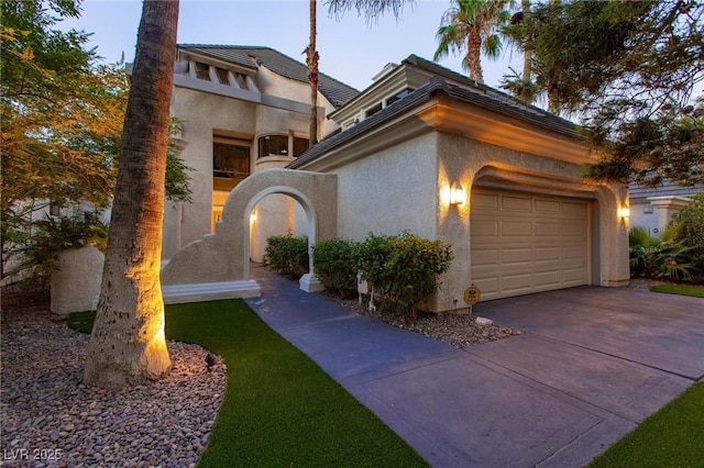 view of front of home featuring driveway, an attached garage, and stucco siding