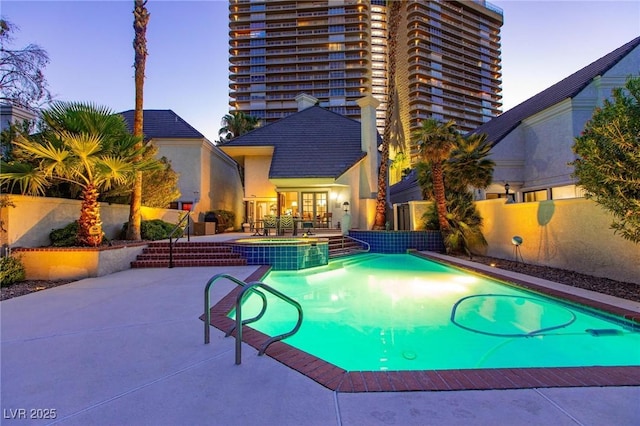 view of swimming pool with a pool with connected hot tub, fence, and a patio