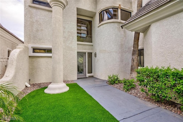 entrance to property with fence and stucco siding