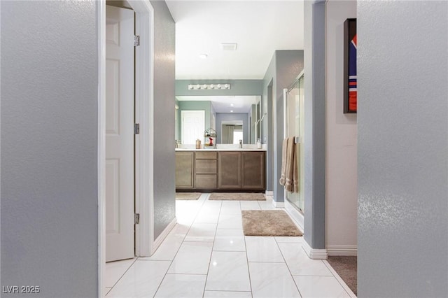 corridor featuring sink and light tile patterned flooring