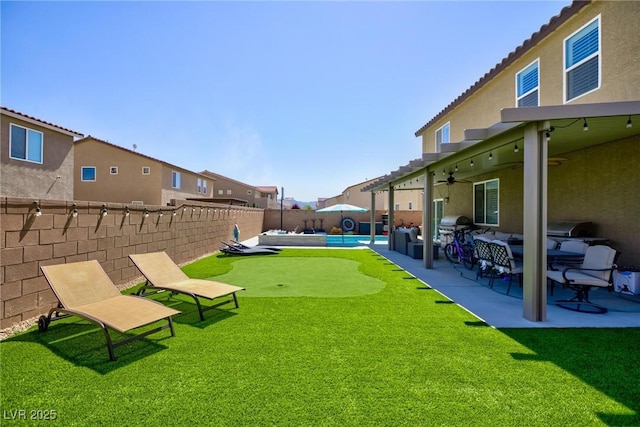 view of yard with ceiling fan, a swimming pool, and a patio