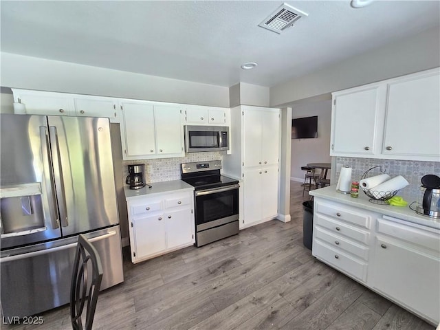 kitchen featuring decorative backsplash, white cabinets, and stainless steel appliances