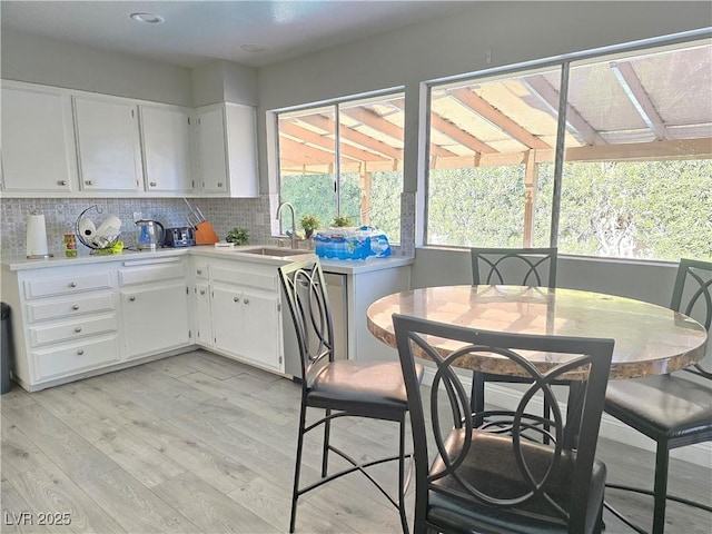 kitchen featuring dishwashing machine, backsplash, white cabinets, and sink