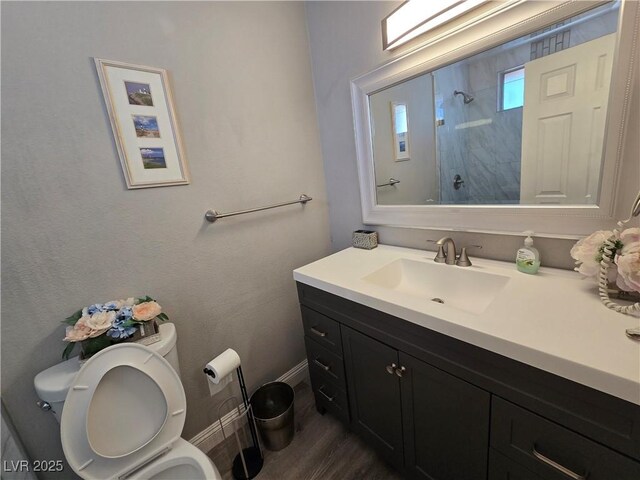 bathroom featuring toilet, vanity, wood-type flooring, and a shower