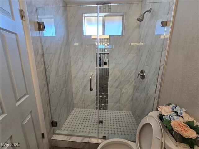 bathroom with toilet and a shower with shower door