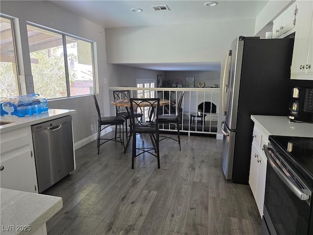 kitchen featuring stainless steel dishwasher, white cabinets, dark hardwood / wood-style flooring, and electric range oven