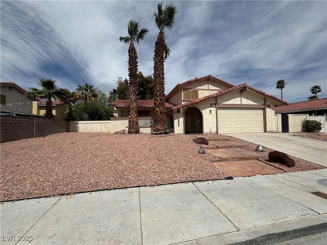 mediterranean / spanish home with a tile roof, driveway, fence, a garage, and stucco siding
