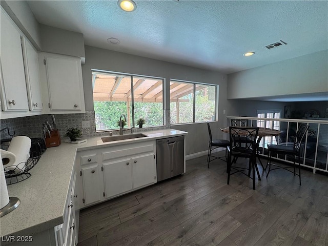 kitchen featuring white cabinets, dark wood finished floors, stainless steel dishwasher, and a sink