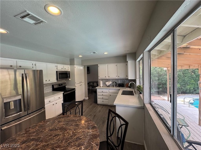 kitchen featuring tasteful backsplash, a sink, light countertops, appliances with stainless steel finishes, and visible vents