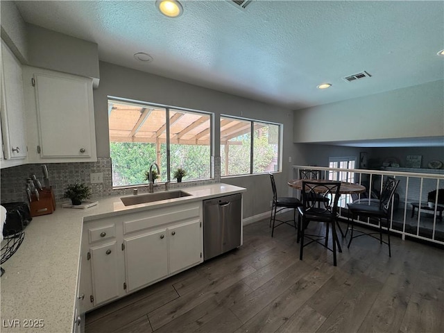 kitchen featuring stainless steel dishwasher, a sink, light countertops, white cabinetry, and visible vents