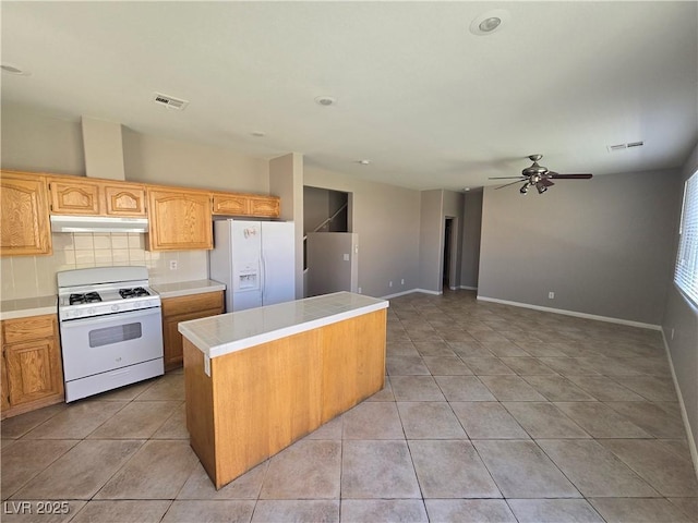 kitchen featuring decorative backsplash, white appliances, a kitchen island, and light tile patterned flooring