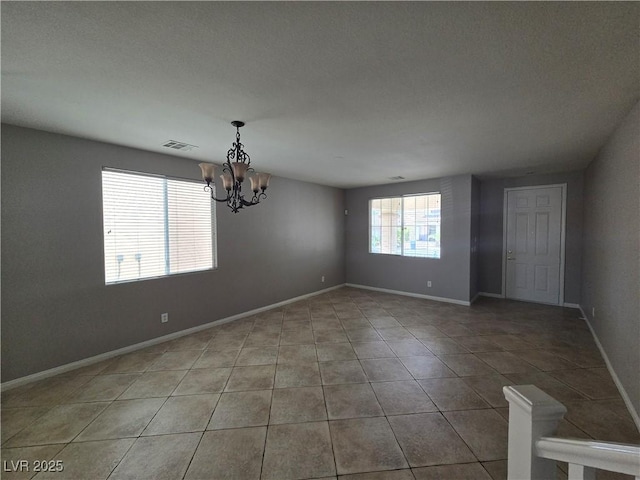 spare room with tile patterned flooring and a chandelier