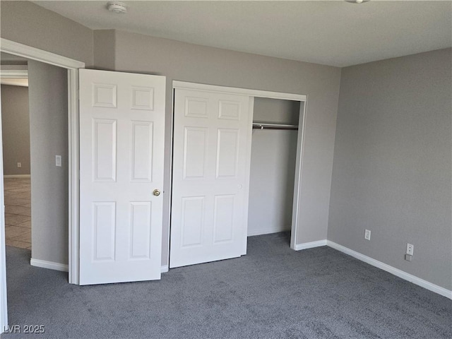 unfurnished bedroom featuring dark carpet and a closet