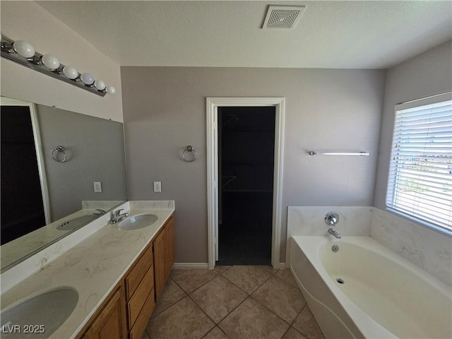 bathroom featuring vanity, tile patterned flooring, a bathtub, and a healthy amount of sunlight