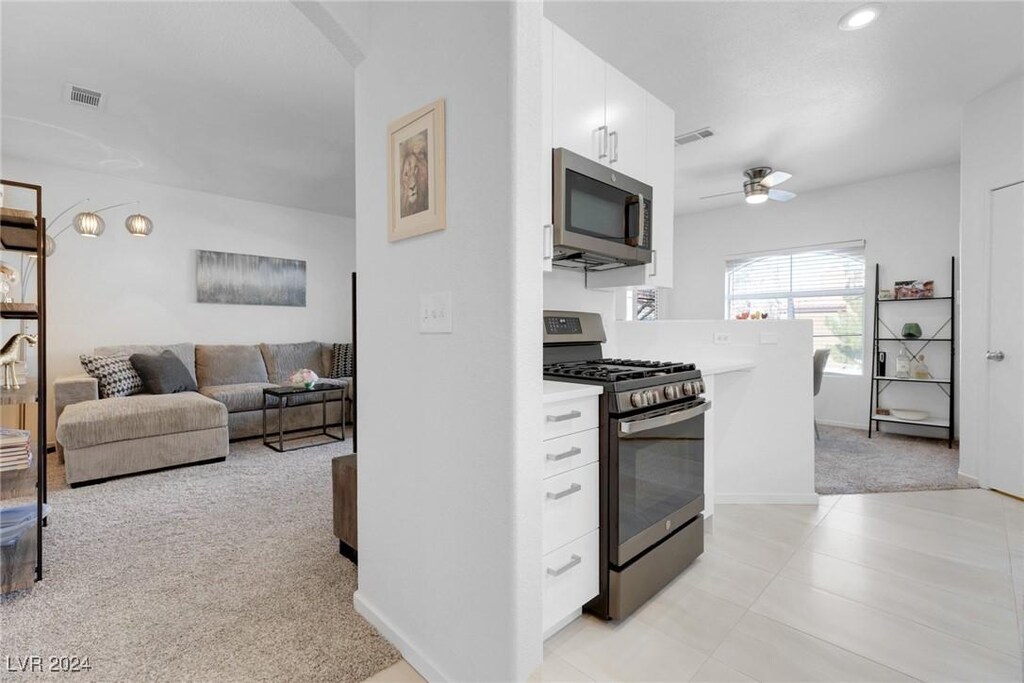 kitchen featuring white cabinets, ceiling fan, light colored carpet, and stainless steel appliances