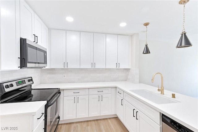 kitchen with appliances with stainless steel finishes, backsplash, sink, white cabinets, and hanging light fixtures