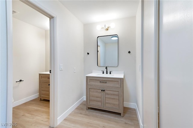 bathroom with wood-type flooring, vanity, and an inviting chandelier