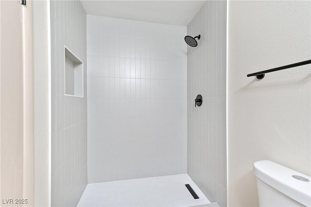 bathroom featuring toilet and a tile shower