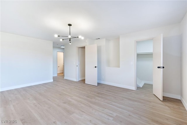 unfurnished bedroom with a closet, light hardwood / wood-style floors, and an inviting chandelier