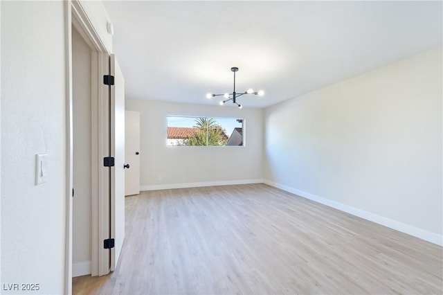 spare room with light hardwood / wood-style flooring and a chandelier