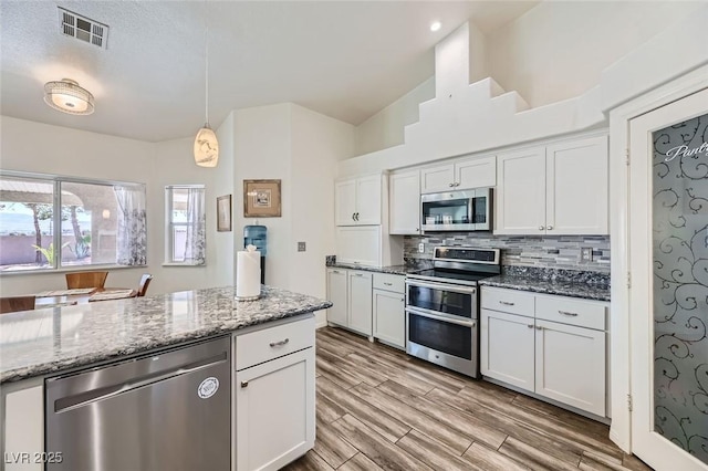 kitchen featuring stainless steel appliances, decorative light fixtures, stone countertops, and white cabinets