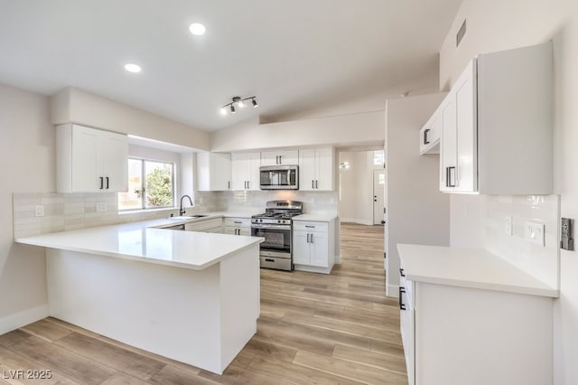 kitchen featuring white cabinetry, sink, stainless steel appliances, kitchen peninsula, and light hardwood / wood-style floors