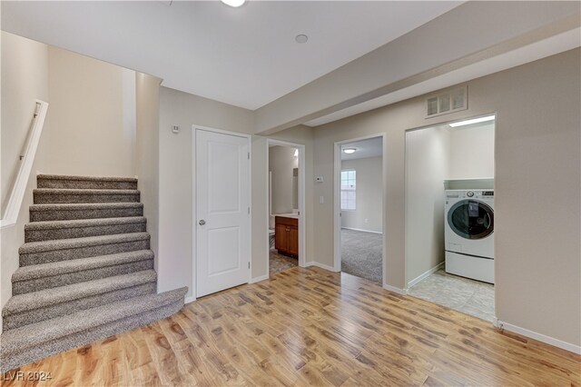 laundry area with washer / clothes dryer and light wood-type flooring