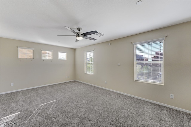 carpeted empty room featuring ceiling fan and a wealth of natural light