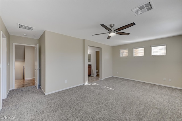 unfurnished bedroom featuring ensuite bath, light colored carpet, and ceiling fan