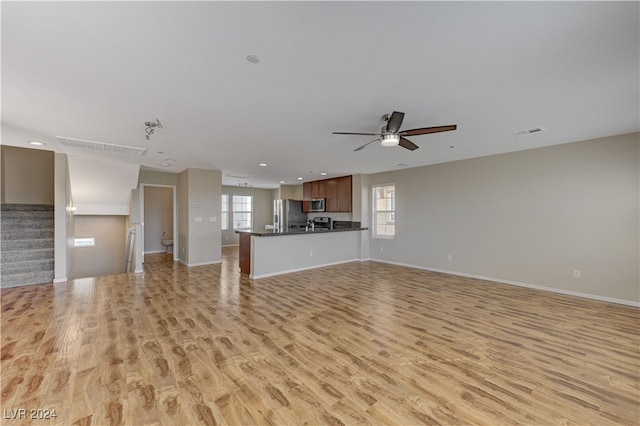 unfurnished living room featuring ceiling fan and light wood-type flooring