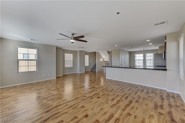 unfurnished living room featuring ceiling fan, light hardwood / wood-style floors, and sink