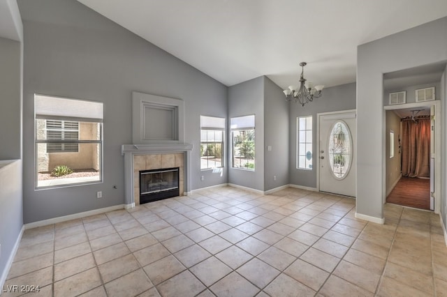 entrance foyer with a fireplace, light tile patterned flooring, a chandelier, and lofted ceiling