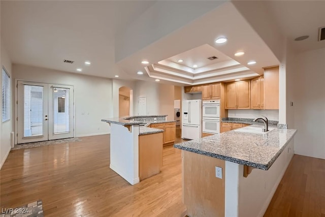 kitchen with a tray ceiling, kitchen peninsula, a breakfast bar, and white appliances