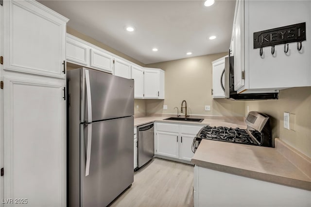 kitchen with white cabinetry, sink, light hardwood / wood-style flooring, and stainless steel appliances