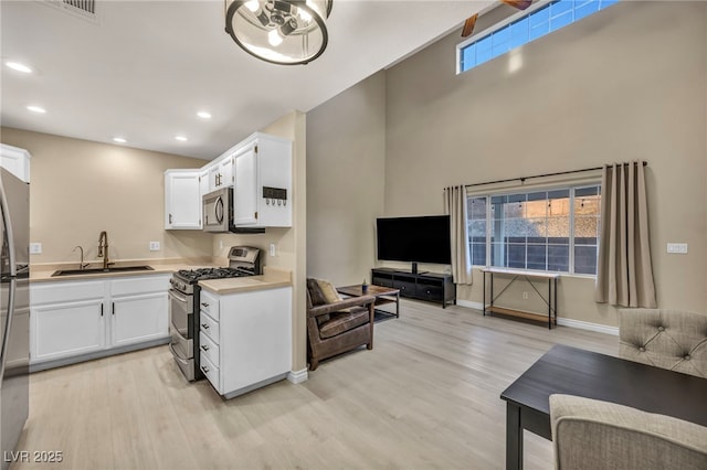 kitchen with white cabinetry, sink, light hardwood / wood-style floors, and appliances with stainless steel finishes