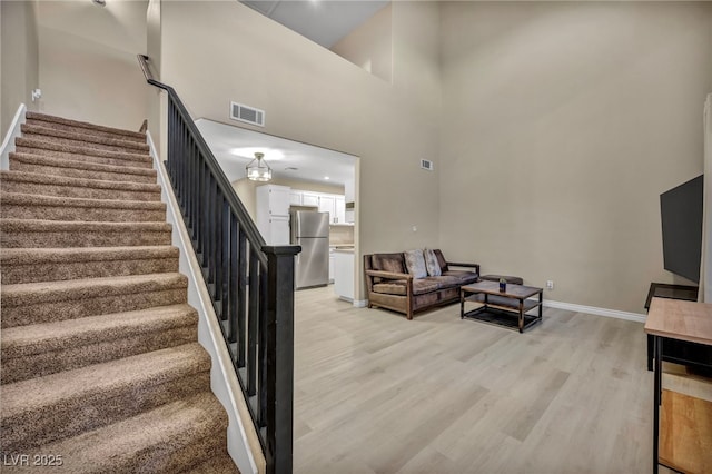 stairway with hardwood / wood-style flooring and a high ceiling