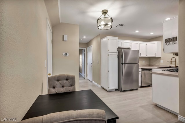 kitchen with sink, decorative light fixtures, a chandelier, stainless steel appliances, and white cabinets