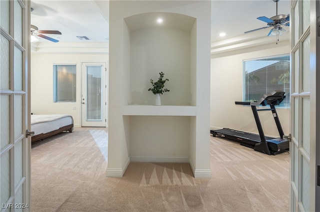 corridor with light carpet, french doors, and a tray ceiling