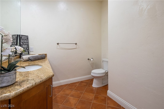 bathroom with toilet, vanity, and tile patterned floors