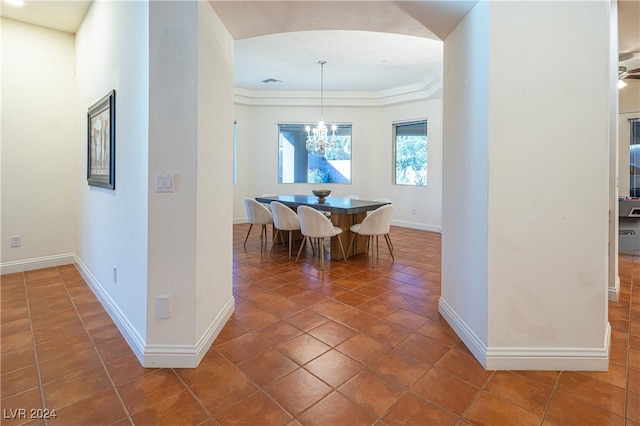 hallway featuring a raised ceiling, an inviting chandelier, and dark tile patterned floors