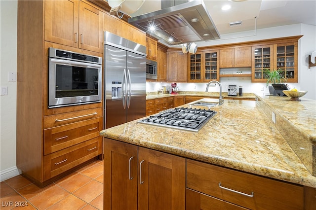 kitchen with light stone countertops, sink, built in appliances, island range hood, and light tile patterned flooring