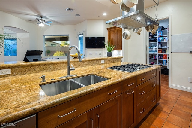 kitchen featuring ceiling fan, sink, light stone counters, dark tile patterned floors, and island range hood