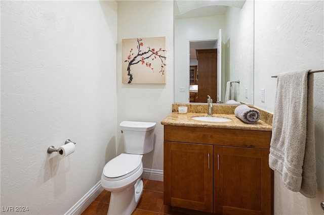 bathroom with toilet, vanity, and tile patterned floors