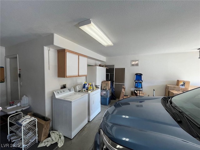 clothes washing area featuring cabinets, a textured ceiling, and independent washer and dryer