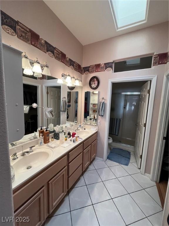 bathroom with tile patterned flooring, vanity, a skylight, and toilet