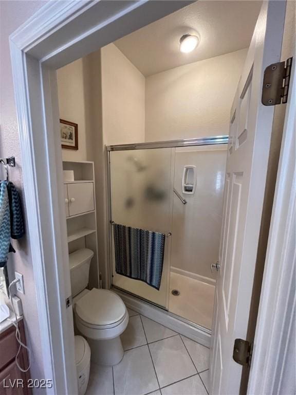 bathroom with tile patterned floors, a shower with shower door, and toilet