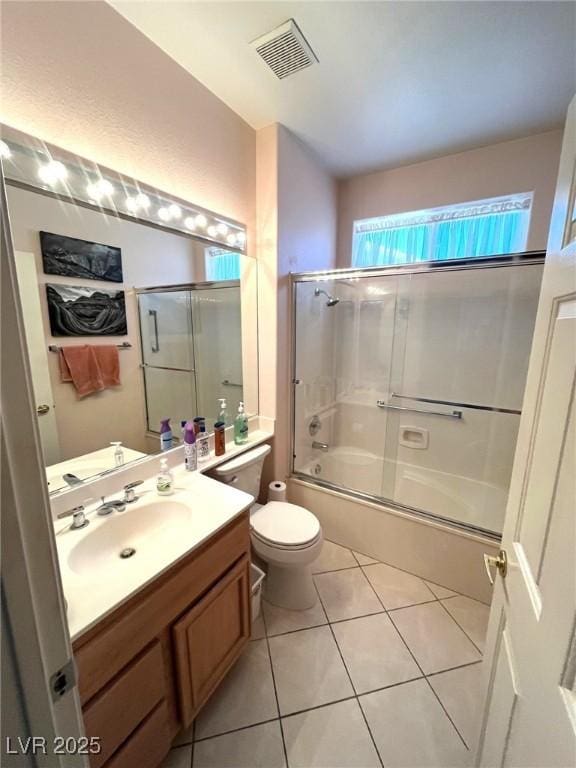 full bathroom with shower / bath combination with glass door, vanity, tile patterned floors, and toilet