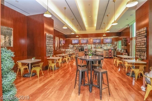 dining room with light wood-type flooring and wooden walls