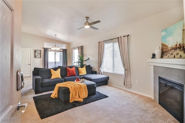 living room featuring plenty of natural light, lofted ceiling, ceiling fan with notable chandelier, and a tile fireplace