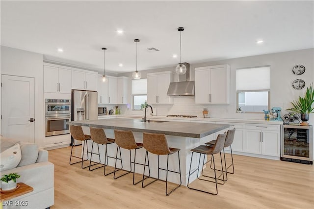 kitchen with white cabinets, sink, stainless steel appliances, and an island with sink